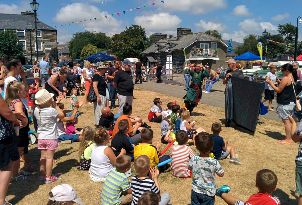 Jay Gatling as the Wizard of Conwy, performing to a crowd of people on a beautiful sunny day.