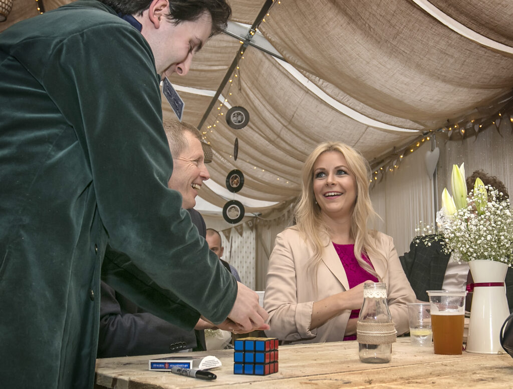 Magician Jay Gatling shows a smiling woman a card trick at a wedding in North Wales