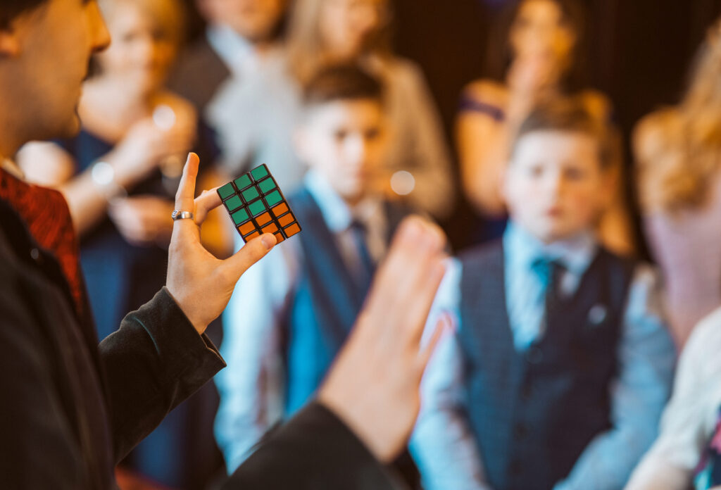 Close up of a Rubik's cube magic trick with attentive crowd in the background.