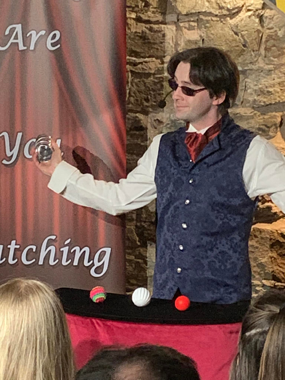 Jay Gatling smiles as he performs the cups and balls.