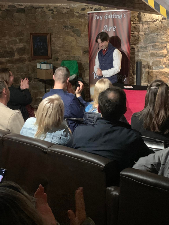 A full audience applauds as Jay Gatling performs a magic trick.